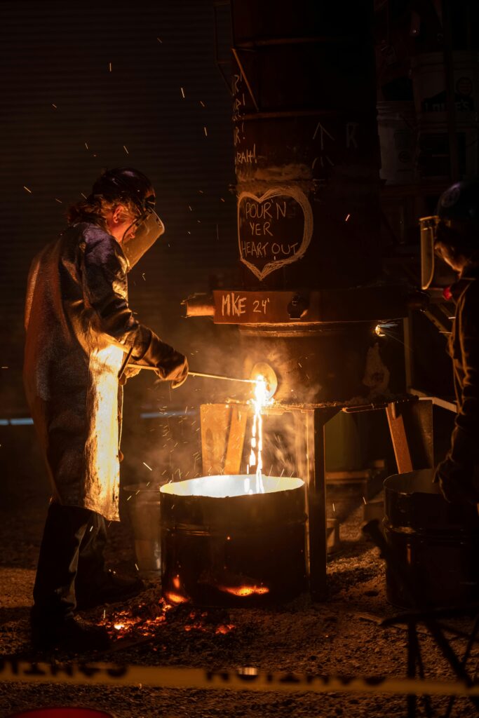 A worker pours molten metal in an industrial setup at night in Milwaukee, Wisconsin.